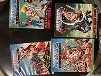 Top view of three He-Man and the Masters of the Universe comics laid out, colorful covers visible showing He-Man and various characters.