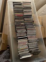 Long shot of large plastic storage bin filled with many stacks of CD cases, showing quantity and mixture of CDs