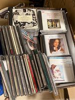 First photo showing a box filled with multiple classical music CDs stacked vertically and some horizontally, including visible artwork.