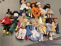 Top-down image of 15 McDonald’s figurines arranged closely on a gray surface showing variety of costumes, colors and styles.
