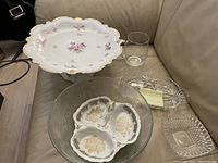 Overview of various glassware and porcelain serving items including glasses, candy trays, glass bowl and glass platter.