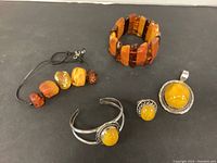 All five pieces: adjustable amber bead bracelet on leather cord, stretchy amber bead bracelet, silver-tone cuff bracelet, amber cabochon ring, amber cabochon pendant