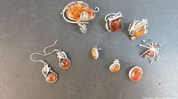 All items laid out: oval brooch, spider brooch, two rings, three pairs of earrings