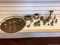 Wide view showing large brass tray with various brass items including napkin rings and figurines