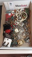 Full view of assorted exotic jewelry including earrings, necklaces, bracelets with elephant motifs and tribal style elements inside a box.
