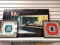 Photo of two framed Molson beer signs and Boulevard of Broken Dreams poster hanging on a wall.