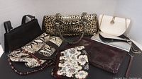 Overview of all 7 purses and clutches showing variety of colors and patterns including leopard print, snakeskin, metallic silver and floral patterns.