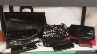 All items in the lot displayed together: eel skin briefcase, multiple purses and wallets in black and silver tones.