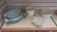 Photo showing the entire lot including the blue Pyrex mixing bowls nested, Corningware measuring cup, Pyrex small bowls with lids in clear view