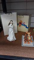Photo of Royal Doulton Embrace figurine in front of its white original box, next to Winnie the Pooh Tigger box and figure.