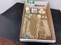 Overview of the entire lot showing various necklaces, brooches, and earrings arranged in a box.