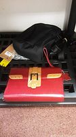 Two travel wallets displayed side-by-side, red wallet in front and black wallet behind on shelf