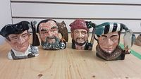 Front view of all four Royal Doulton Toby mugs showing detailed character faces and accessories.