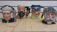 Four small Toby mugs arranged in a row showing front view of each character design.