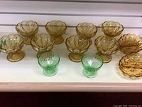 Full lot photo showing 8 orange dessert glasses, 2 green small dessert glasses, and 2 orange appetizer dishes arranged in a row.