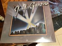 Front cover of 'Jo Jo Gunne' sealed vinyl album showing band name and city skyline background.