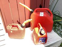 Photo showing all three red plastic fuel containers in varying sizes with spouts and handles, arranged on a white surface.