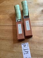 Photo showing two vintage boxed Japanese scrolls with rolled scrolls protruding from orange boxes labeled in Japanese, each featuring small animal illustrations on the box side.