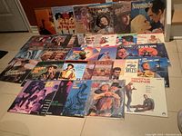 Photo showing full spread of 30 laser discs arranged in 3 rows on floor including titles mentioned by seller and two sealed discs Oliver and The Music Man.