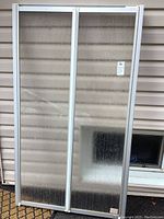 Photo of ShowerLux shower enclosure with textured plastic folding doors in metal frame, showing overall size and condition.