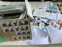 Overview of vintage stamps attached to a sheet, with envelopes and miscellaneous paper items in the background.