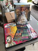 Both Barbie doll in original packaging and Elmer's Deluxe Artist Set on a table.