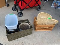 Photo showing two wicker baskets next to a metal container holding ceramic planters and plastic bins on garage floor