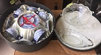 Two clear glass serving dishes placed on a white cloth, including an oval divided dish and a round bowl with etched floral decoration.