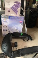 Boxed Homedics Bubble-Bliss Elite foot spa with Conair hot cold pack visible in box photo along with black Brookstone neck and shoulder massager laid on floor.