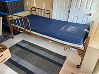 Full view of Invacare motorized home care bed with Solace mattress, showing side rails, wheels, and mattress cover with branding.