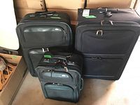 Three black luggage pieces arranged vertically, showing size differences and front zipper compartments.