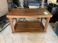 Front view of rectangular brown laminated particle board side table with four vertical supports and lower shelf, standing on caster wheels.