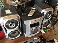 Front angle of Sony MHC-GX35 stereo system with remote on top and two speakers on each side placed on a wooden table.