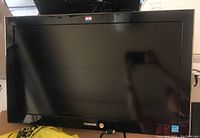 Front view of Toshiba 26-inch TV showing black screen and frame, brand logo visible.