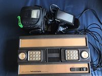 Mattel Intellivision Model 2609 console with Garmin Nuvi 1307 GPS device and Lowepro case on blue fabric background.