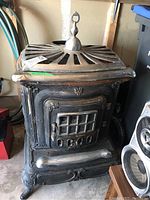 Front view of the cast iron wood burning stove highlighting the grated door and decorative top vent.