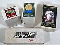 Four white cardboard boxes of baseball cards labeled with various brands and sets.