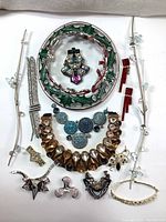Full overview of all Swarovski crystal jewelry parts in the lot including large hollow wreath brooch, bracelet, earrings, and assorted components.