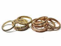 Multiple Swarovski rings in gold and rose tone metal with pave settings arranged in two groups showing single band rings with crystals all around.