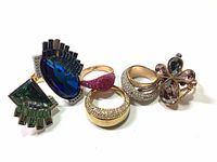 Six Swarovski rings displayed in a cluster showing various designs, gemstone colors, and pave crystal settings.