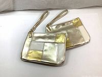 Pair of metallic rectangular mini pouches with gold and silver patchwork design laid on a white surface.