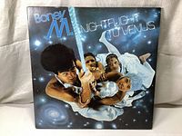 Front cover of Boney M. Nightflight To Venus album showing the band members climbing a rope in space-themed background