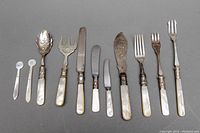 Photo showing entire assortment of eleven assorted cutlery pieces laid out horizontally on a flat gray surface.