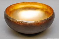 Side angle view showing textured bronze exterior and gold plated interior of the round artisan bowl.