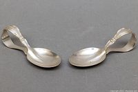 Top view of two 3.5-inch sterling silver baby spoons with curved handles, showing their size and shape.