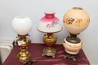 Three old hurricane lamps converted to electric displayed on table