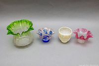 Full frontal view of all four glass lampshades in the lot showing size and color details