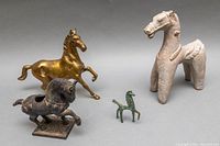 Four vintage horse sculptures displayed together showing variety in size and material.