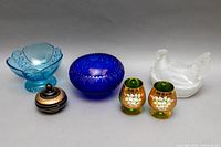 Full lot overview showing six glass and crystal items including cobalt blue bowl, frosted hen on nest, blue bowl, lidded container, and painted glasses