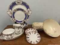 Overall assortment of dinnerware and serveware showing plates, creamer, sugar bowl, and larger serving bowls.